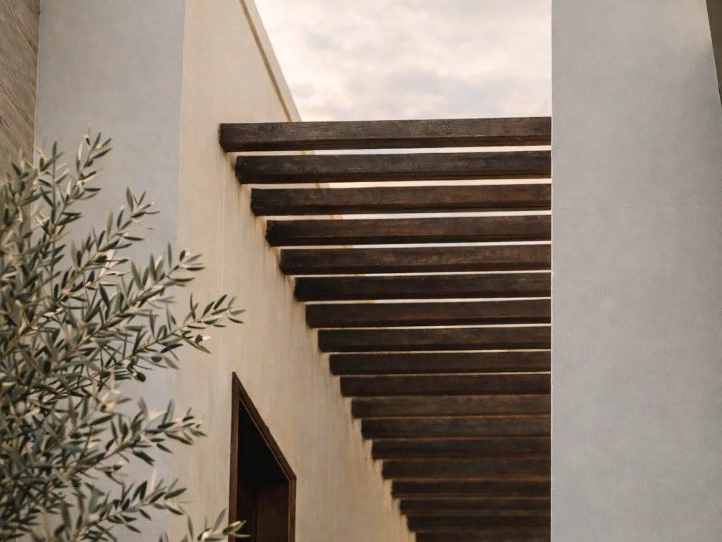 Farmhouse wall with a wooden pergola and an olive tree at Olive Farms